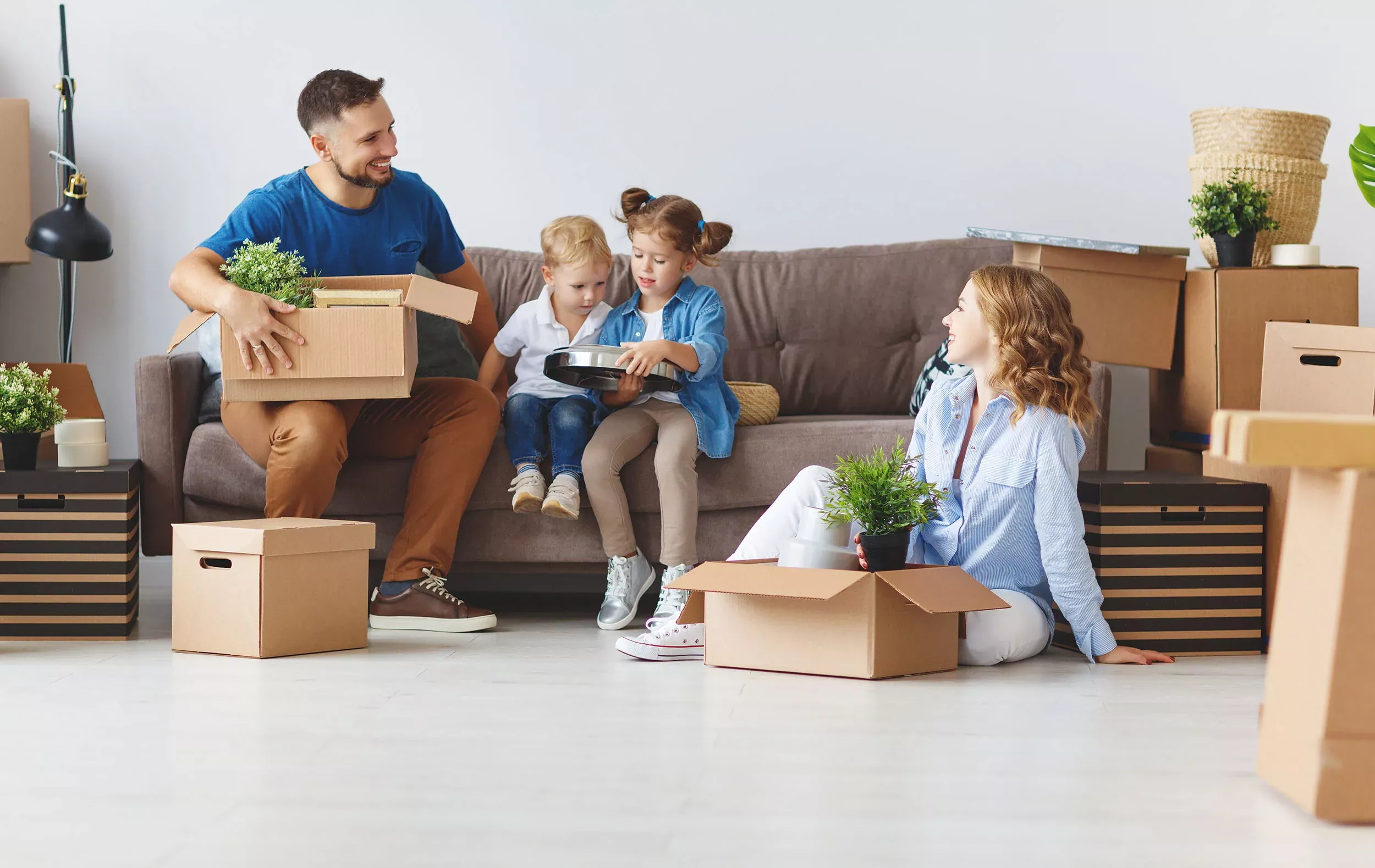 Eine Familie packt ihre Sachen in Umzugskartons, während die Kinder tatkräftig mit anpacken.